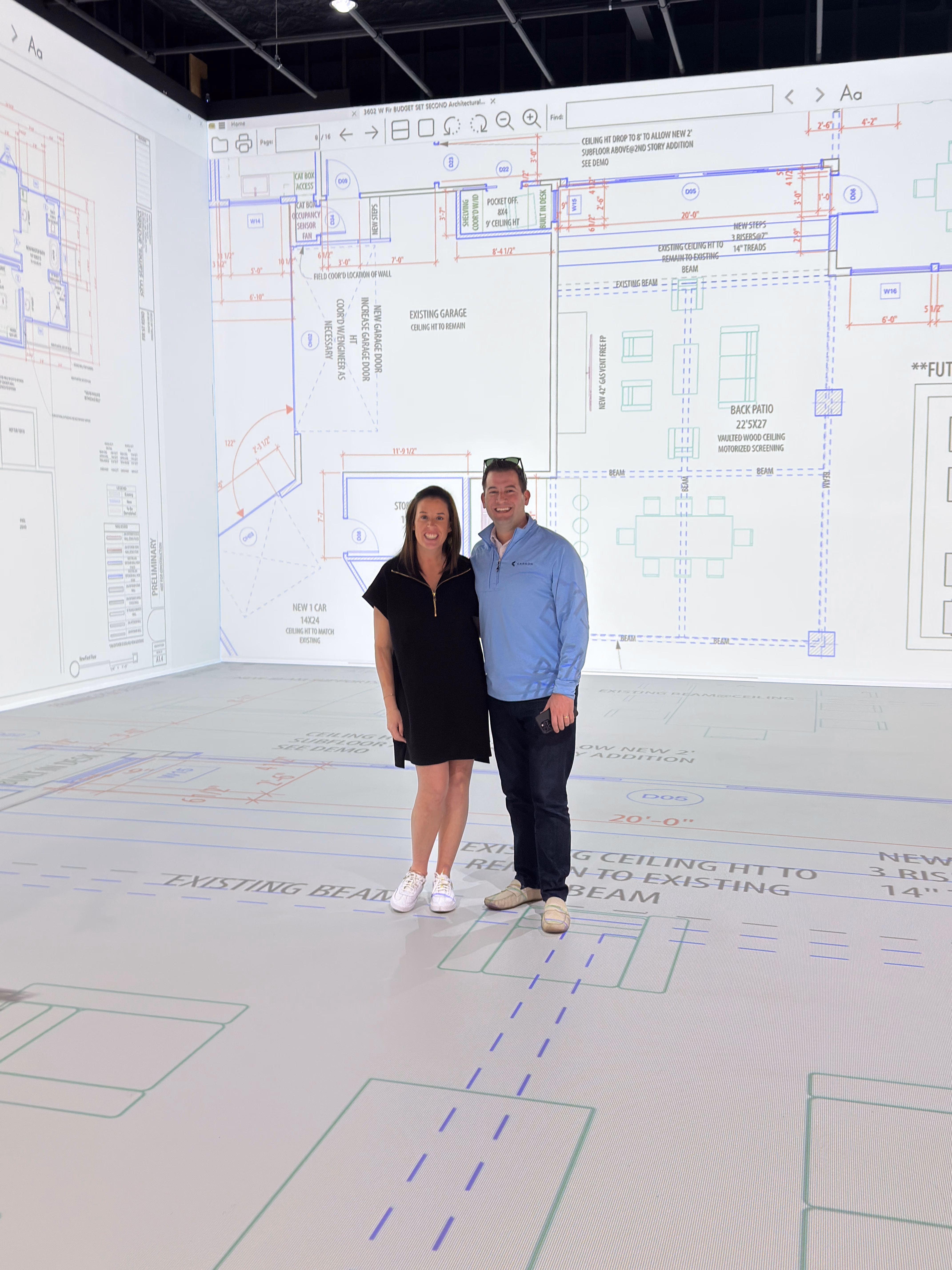 A homeowner couple walking through their projected floor plan inside the Walk Your Plans NWA studio