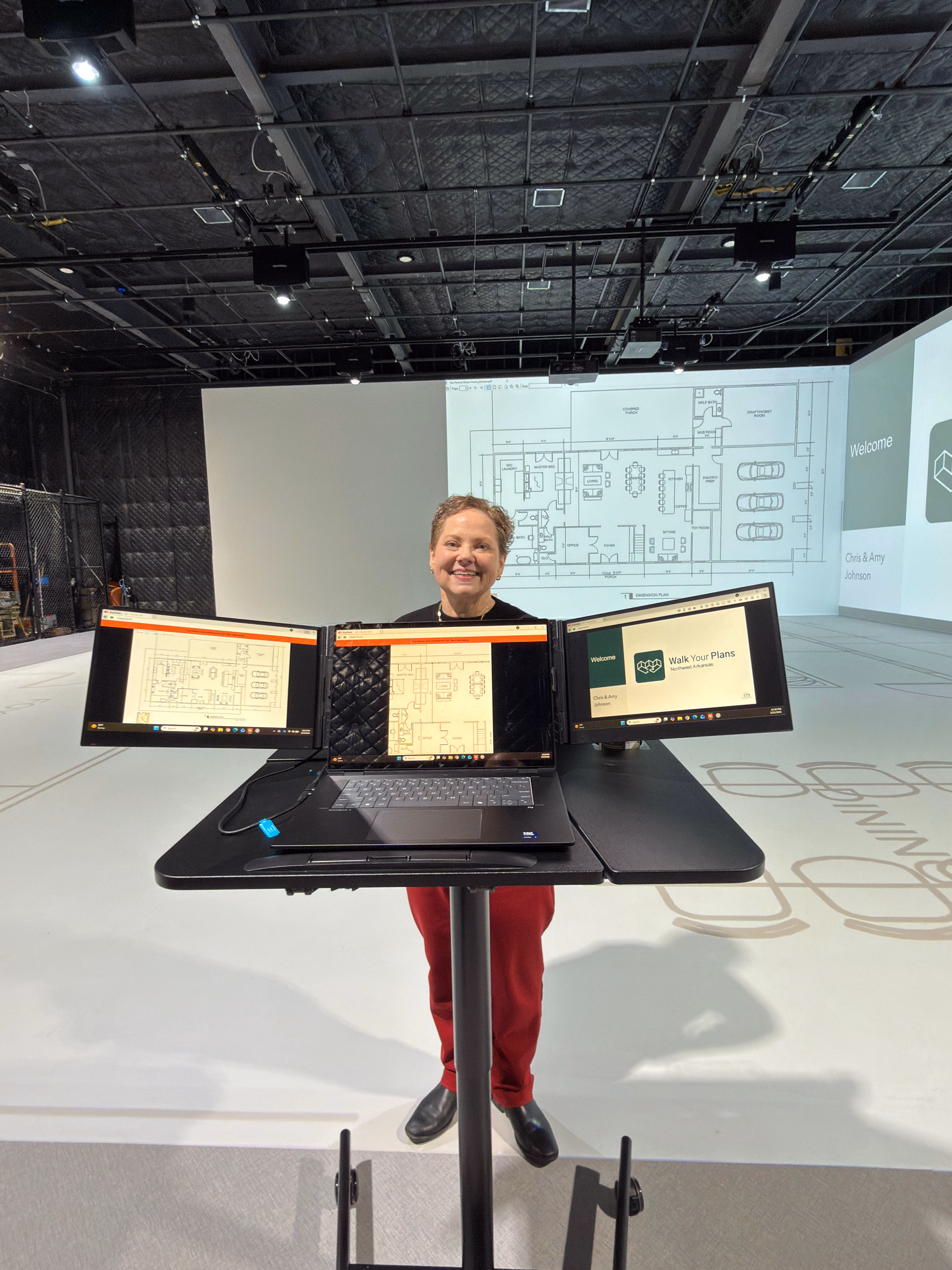 A Walk Your Plans operator at a triple-monitor workstation adjusting projected plans during a session