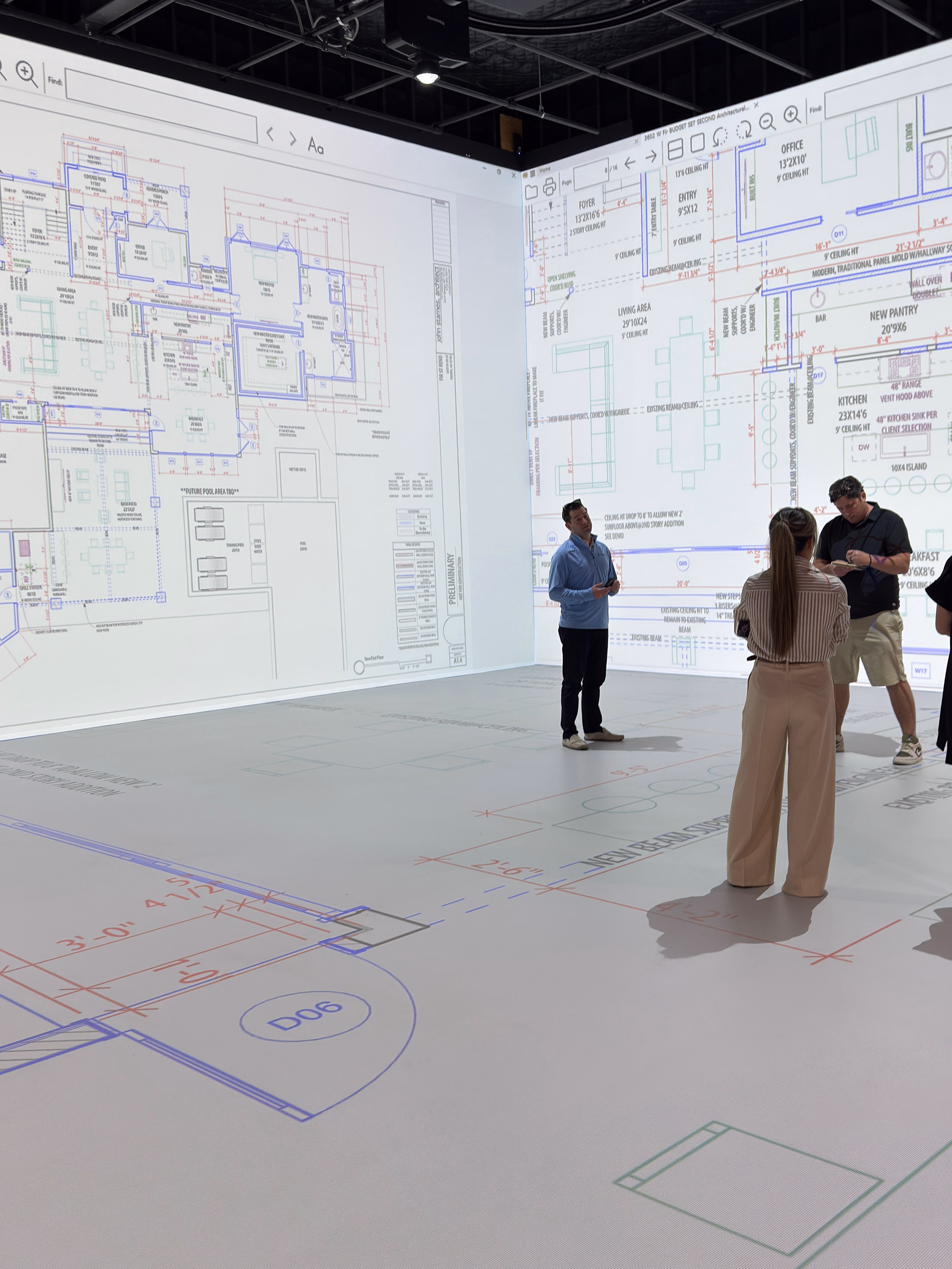 A group of people walking through architectural floor plans projected at full 1:1 scale in the Walk Your Plans NWA studio
