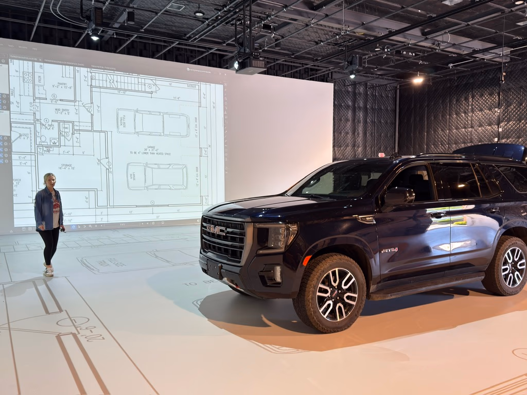 A full-size SUV parked inside a projected garage outline at the Walk Your Plans NWA studio
