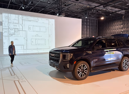 A full-size SUV parked inside a projected garage outline at the Walk Your Plans NWA studio, demonstrating real-world scale